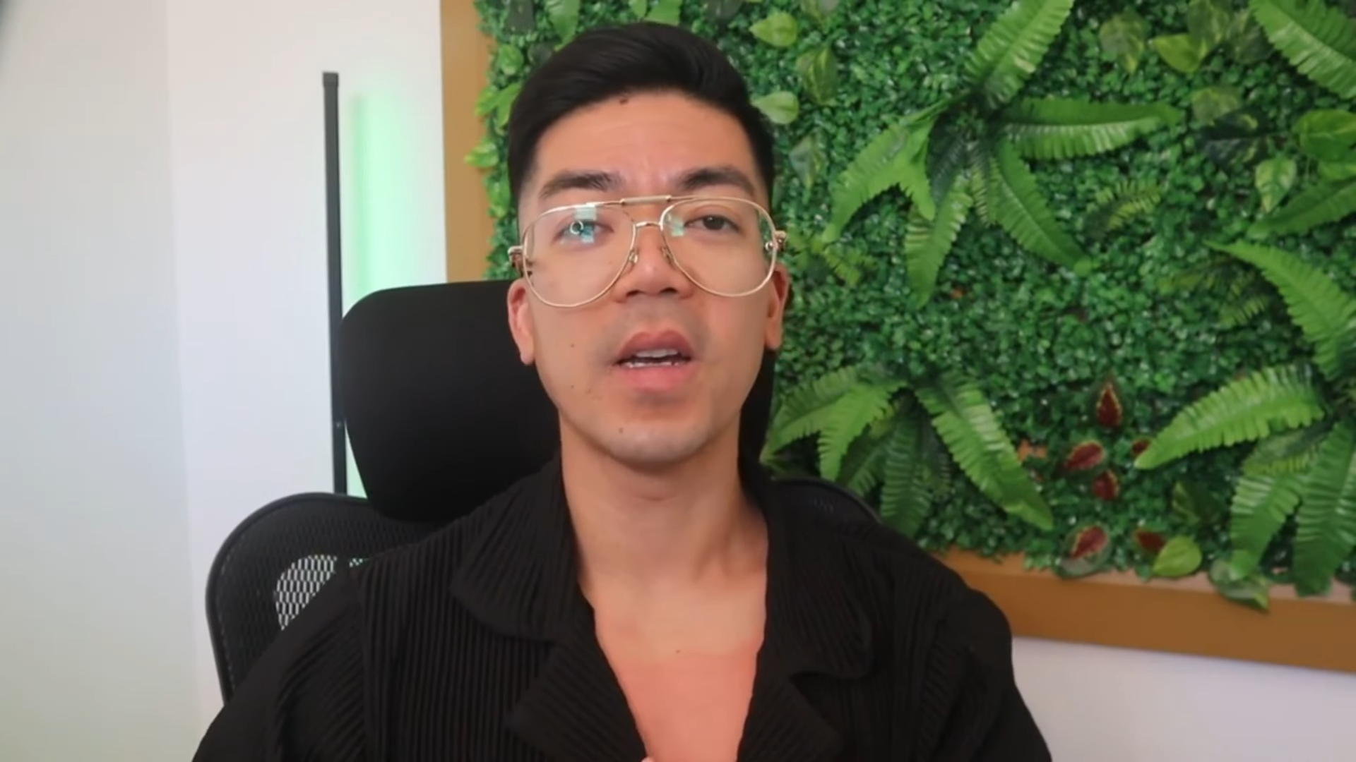 Kevin Gonzales seated in front of a green plant wall